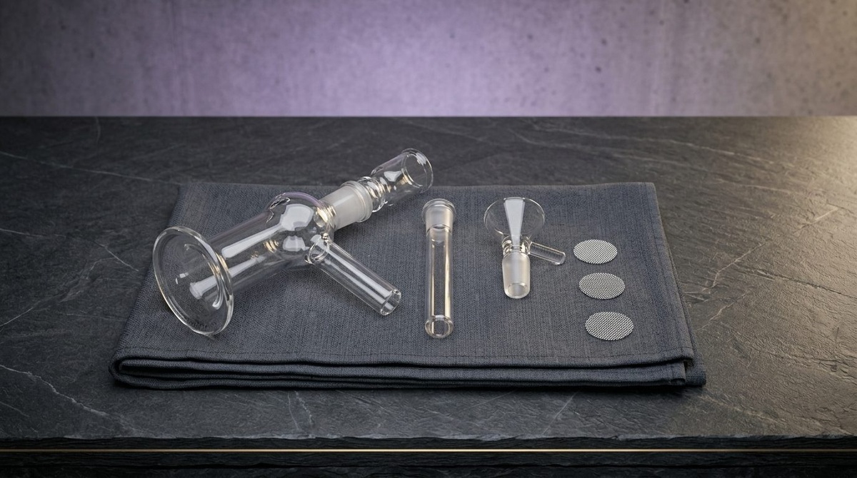 Frisch ausgepackte Glasbong mit Chillum, Kopf und Sieben nebeneinander auf einem Tuch